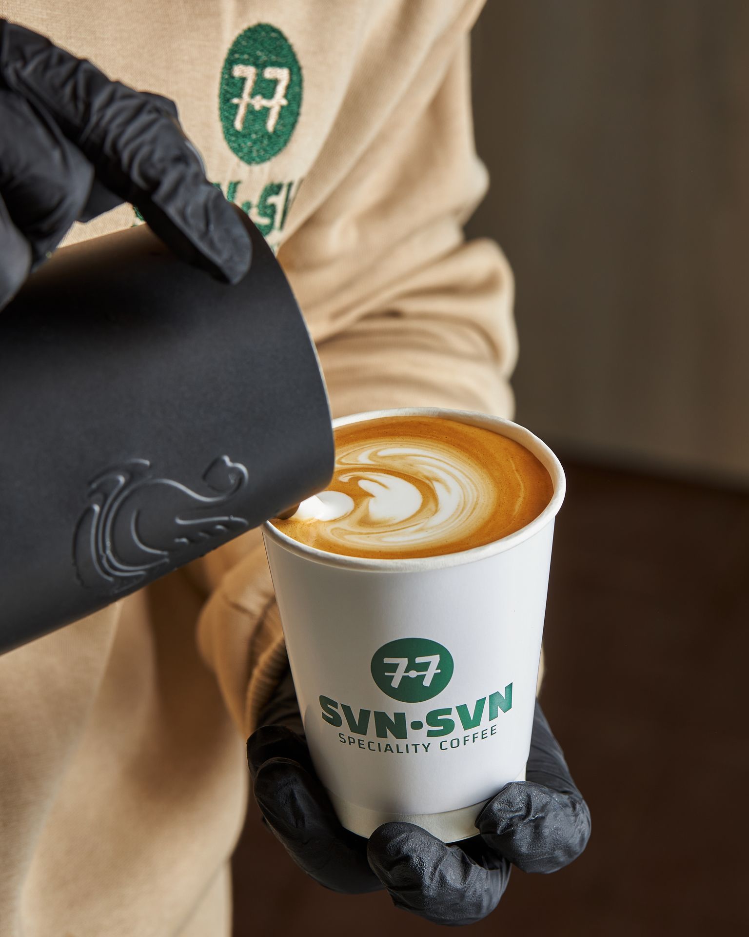 Barista pouring latte art at 7.7 Specialty Coffee